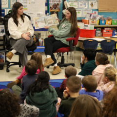 Chelmsford High School National English Honor Society members Ellen Griswold and Maeve Chalmers read to students in Mrs. Bullock's first grade class at South Row Elementary School.