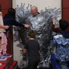 Harrington Elementary School students duct tape Principal Rob Asselin to the gymnasium wall on Thursday, April 30, as a fundraiser for the fourth grade class.