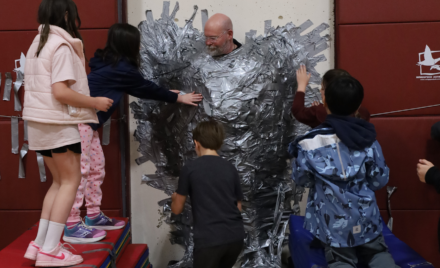 Harrington Elementary School students duct tape Principal Rob Asselin to the gymnasium wall on Thursday, April 30, as a fundraiser for the fourth grade class.