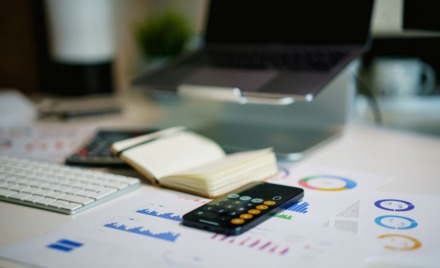 An office desk with smartphone and financial charts